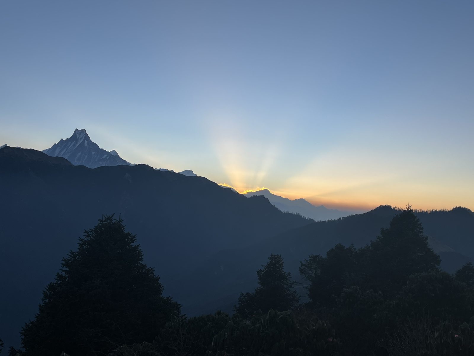 Machapuchare (Fishtail) silhouetted against a sunburst at dawn