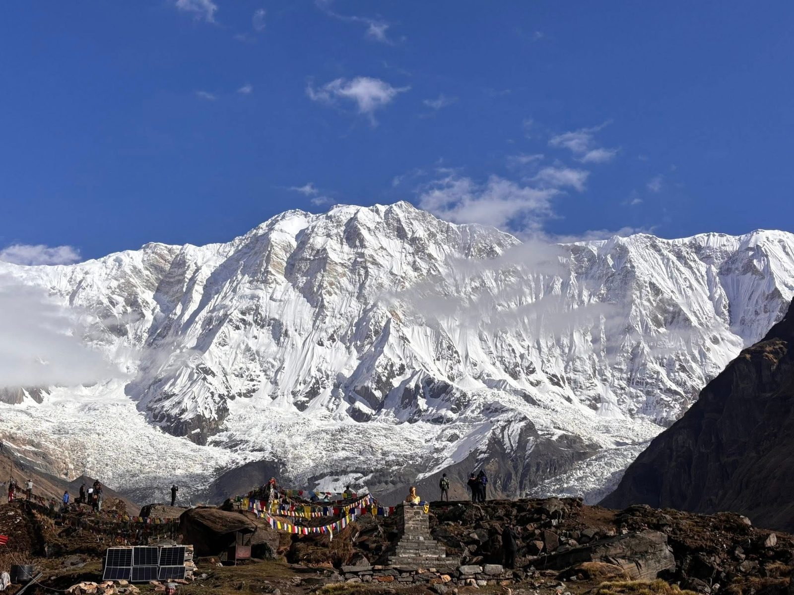 Snow-covered Annapurna massif rising above stone mani walls