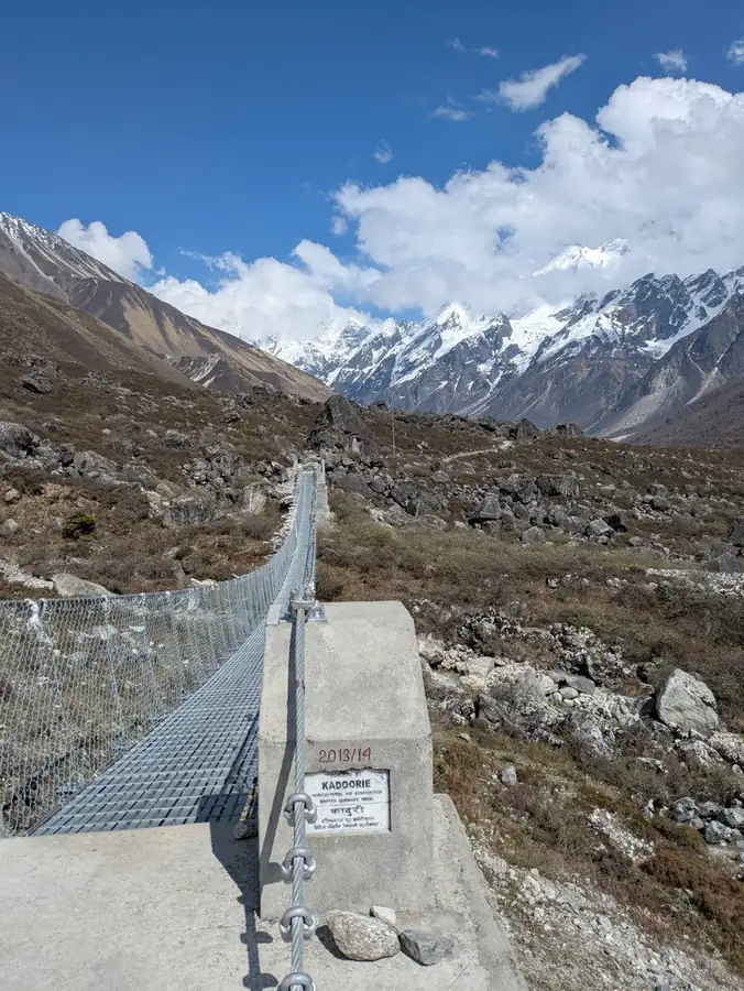 A trekker crossing a suspension bridge over the Langtang river