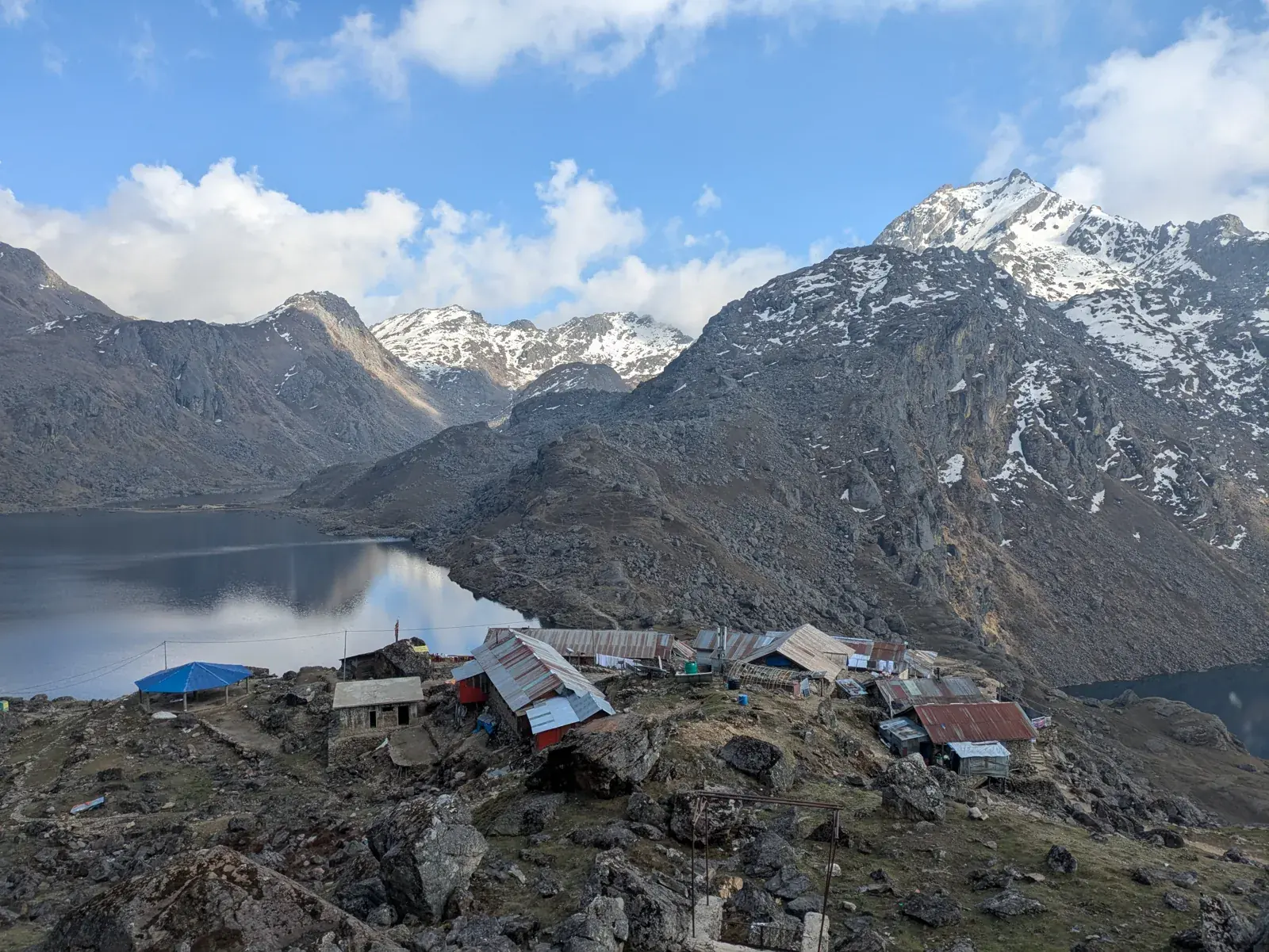 Stone pilgrim lodges beside a Gosaikunda lake under snow peaks