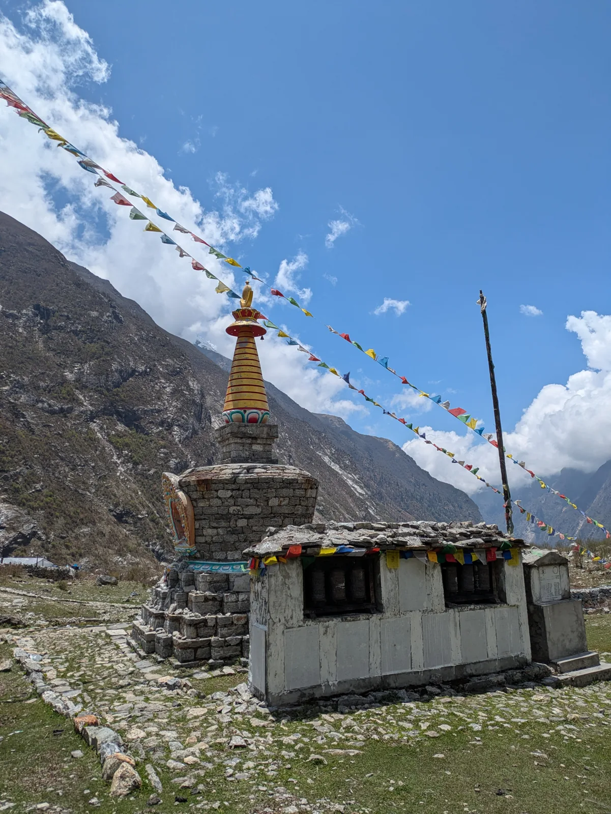 A white chorten hung with prayer flags below snow-covered peaks